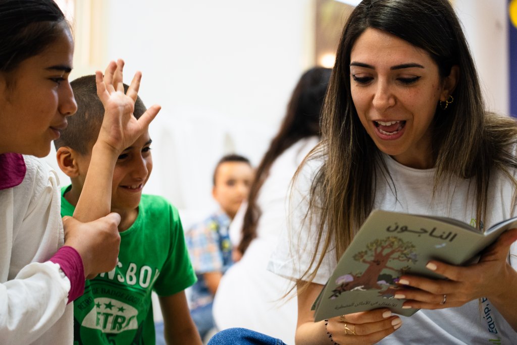 Woman reading Survivors program to children.